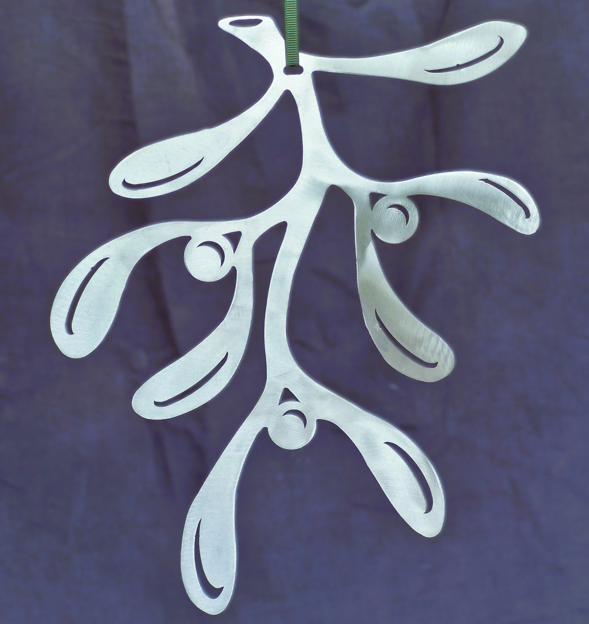Polished silver Mistletoe Christmas ornament against a dark navy background