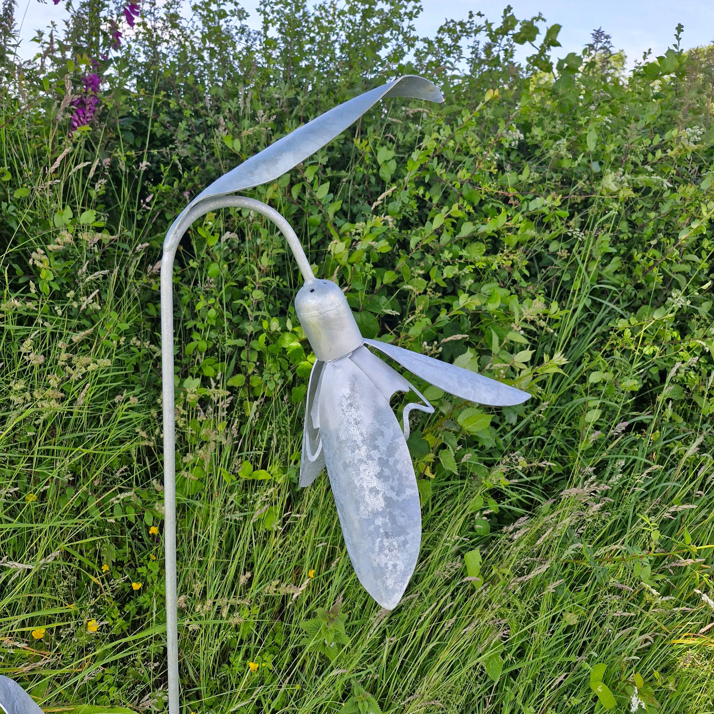 Metal snowdrop sculpture in a grassy outdoor setting